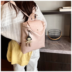 Close-up of light pink PU leather backpack with a cute cartoon girl charm on the side