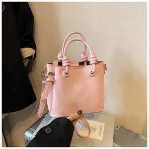 Pink leather bucket bag featuring unique knotted top handles and silver metal hardware details