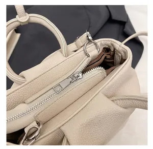 Macro shot of silver metal zipper and textured lychee leather on a cream bucket bag
