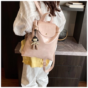 Detail of pink PU leather backpack with magnetic flap and cute cartoon doll pendant