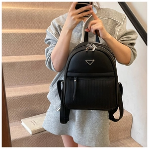 Detailed view of the silver triangular logo and smooth zipper on black leather backpack
