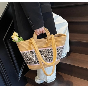 Detail of hand-woven straw tote with striped accent strap and tulip for beach vacation