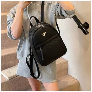Close-up of black lychee grain backpack with metal triangle logo on a model