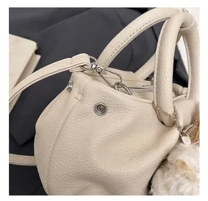 Macro detail of high-quality metal hardware and precise stitching on beige bucket bag