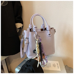 Detail of lavender bucket bag featuring a knotted handle and billiard ball charm