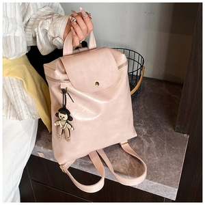 Detail of light pink leather backpack with metallic button and cute cartoon keychain