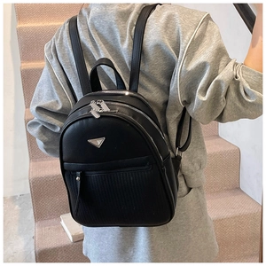 Detail of black pebbled leather backpack with silver triangle logo and striped embossing