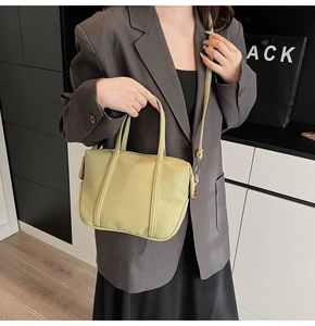 Detailed texture of yellow lychee grain leather on a modern top-handle crossbody bag
