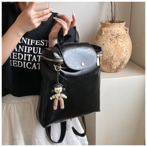 Detail of black oil wax PU leather backpack with gold zippers and a cute cartoon charm