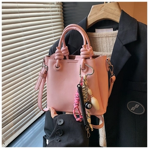 Pink minimalist bucket bag featuring knot handle and trendy billiard ball charms accessory
