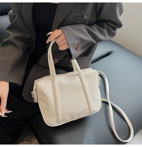 Close-up of cream white lychee pattern faux leather handbag with handles and thin strap