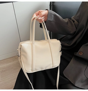 Detail of lychee textured cream PU leather handbag with silver hardware and dual handles