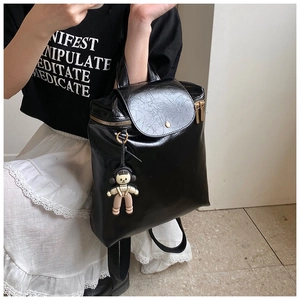 Detail of black glossy PU leather backpack with gold zippers and cartoon charm