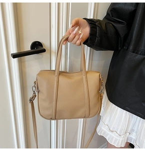 Detail of beige pebbled leather handbag with soft texture and metal strap hook