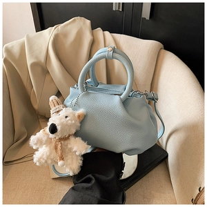 Detail of light blue lychee pattern leather bucket bag with a cute plush puppy charm