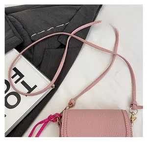 Détail du sac bandoulière rose en cuir grainé avec coutures fines sur une veste de costume