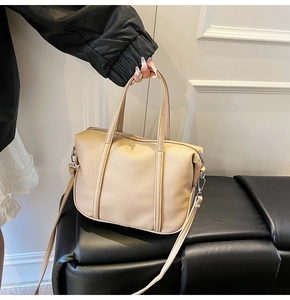 Detail of elegant beige lychee texture handbag with double handles and detachable strap