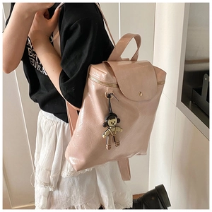 Detail of pink glossy leather backpack with astronaut charm and gold zipper on model