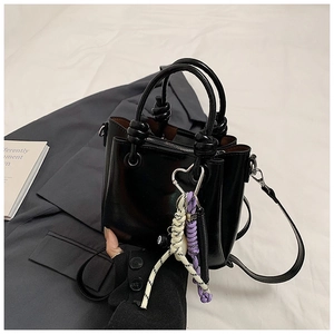 Detail of black leather bucket bag with heart pendant and braided rope decoration