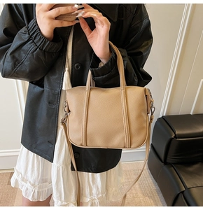 Detail of apricot litchi grain leather texture and dual handle design on handbag