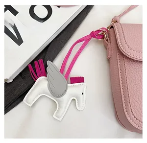Détail d'un charm pégase en cuir blanc avec pompon rose sur un sac à main chic