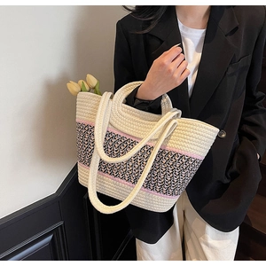 Detail of large woven tote bag with pink stripes and geometric patterns on a beige base