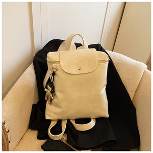 Detail of cream white backpack with magnetic flap and cute cartoon girl charm