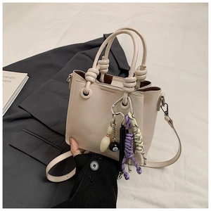Detail of cream leather bucket bag with knot handle and stylish 8-ball charm accessories