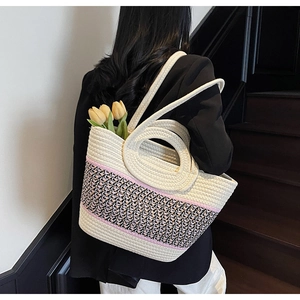 Detail of a woven tote bag featuring ethnic patterns and pink stripes on a model