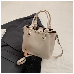 Detail view of the cream bucket bag with silver metal eyelets and fine leather texture