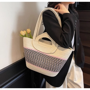 Detail of woven tote bag featuring pink stripes, cream cotton cord, and dual handles