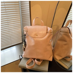 Detail of light pink stylish backpack with glossy finish and cute cartoon charm