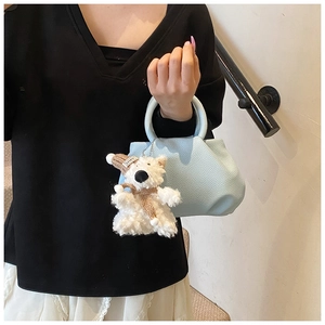 Close-up of light blue pleated bucket bag with lychee texture and cute bear charm