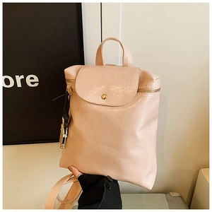 Detail of light peach pink backpack with pleated faux leather texture and gold button