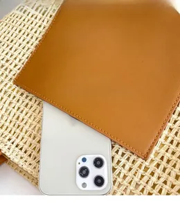 Detail of contrast leather pocket on a woven tote bag with orange stitching and ivory texture