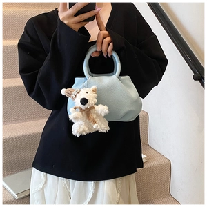 Close-up of light blue pleated bucket bag with dog charm on a street style model