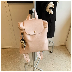 Detailed texture of pink faux leather backpack with a cute bear charm on a display stand