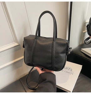Detailed view of black litchi grain PU leather Boston bag with silver hardware and handle