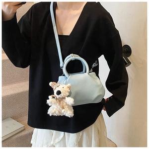 Detail of light blue pleated bucket bag with lychee texture and cute bear charm