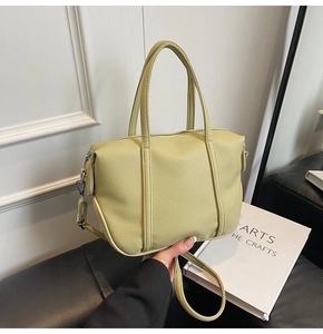 Detail of avocado green textured leather handbag with metallic zipper and durable handles