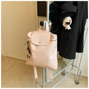 Detail of light pink PU leather backpack with flip cover and black cartoon pendant decoration