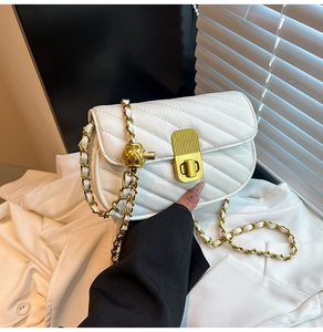 Détail d'un sac bandoulière matelassé blanc avec fermoir doré et bandoulière chaîne