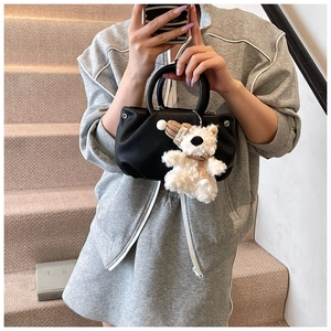 Detail of black lychee grain handbag featuring a cute plush bear charm with Lovely cap