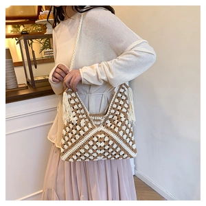 Dettaglio ravvicinato della borsa a tracolla intrecciata con nappe e motivi boho