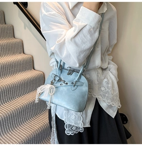 Détail du sac en similicuir bleu clair avec nœud en dentelle et pendentif perle