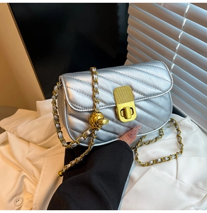 Détail du sac bandoulière matelassé argenté avec chaîne dorée et breloque boule en métal