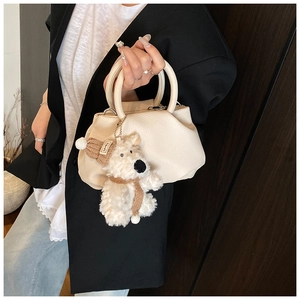 Detail of off-white lychee texture bucket bag with a cute plush bear charm accessory