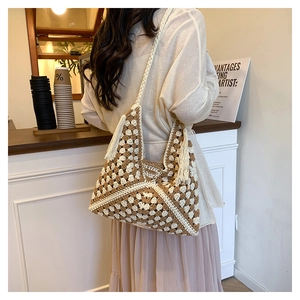 Dettaglio borsa boho in maglia con motivi geometrici marroni e nappa decorativa