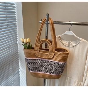 Detail of woven tote bag showing geometric pattern and dual straps on metal stand