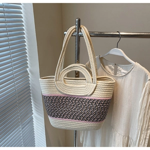 Detail of woven tote bag showing pink striped pattern and dual handle straps